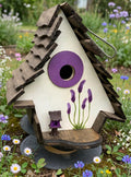 Lilac Crooked House birdhouse among wildflowers
